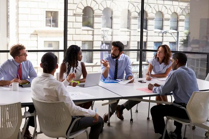 Executives in a modern boardroom discussing corporate strategy with digital charts and planning tools.