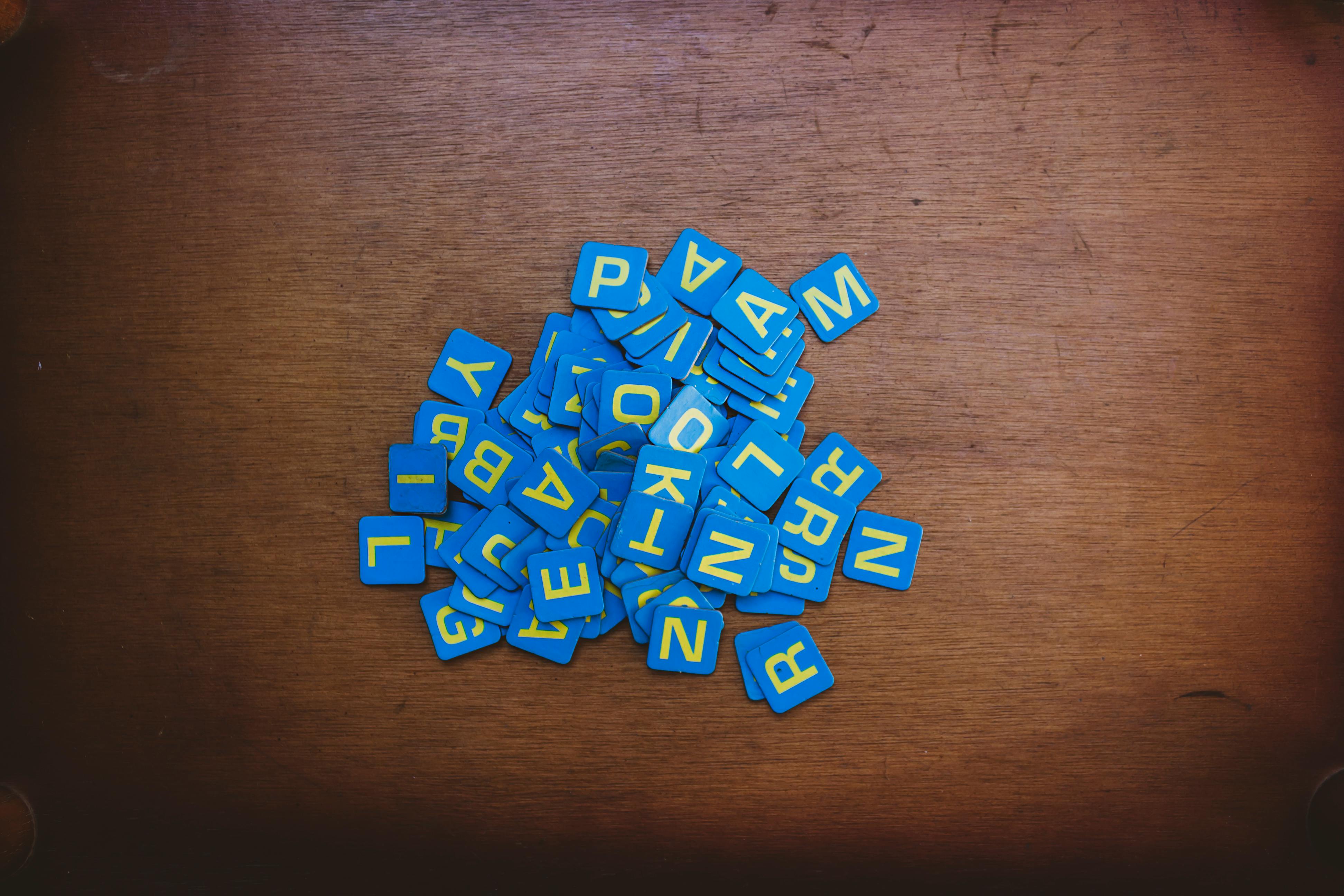 pexels-photo-14249848-14249848 Pile of blue letter tiles on a rustic wooden tabletop, perfect for word games or educational themes.